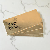 Gold envelopes with 'Happy Diwali' text on a marble surface